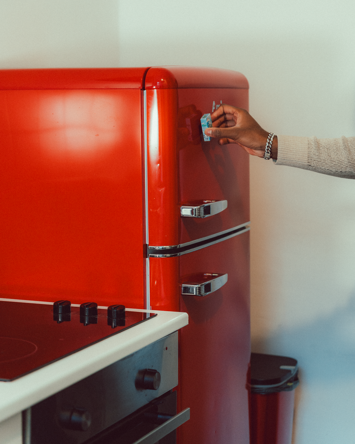 about-01 An arm extends to open a vintage-style red refrigerator, creating a nostalgic kitchen scene.